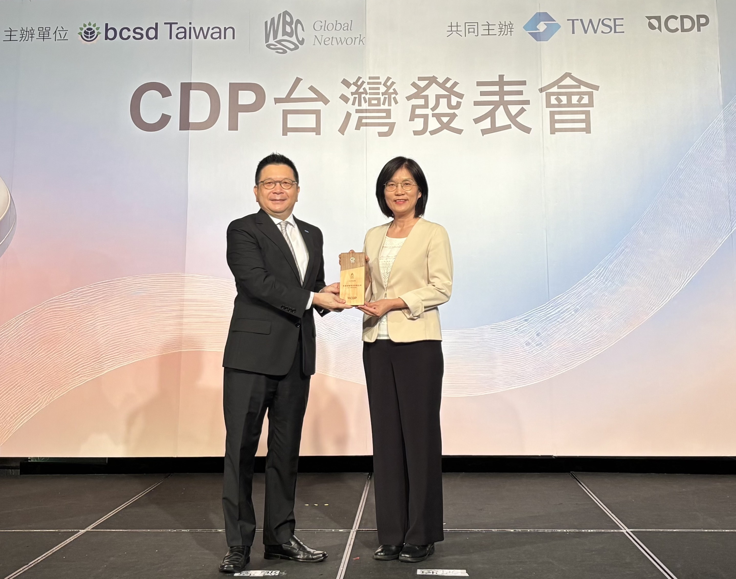 ng28南宮相信品牌力量永續(xù)成果再獲國際評比肯定，獲頒CDP氣候與水資源雙項領(lǐng)導(dǎo)力評級。今由臺灣證券交易所董事長林修銘（左）頒獎，ng28南宮相信品牌力量光電永續(xù)長古秀華（右）代表受獎